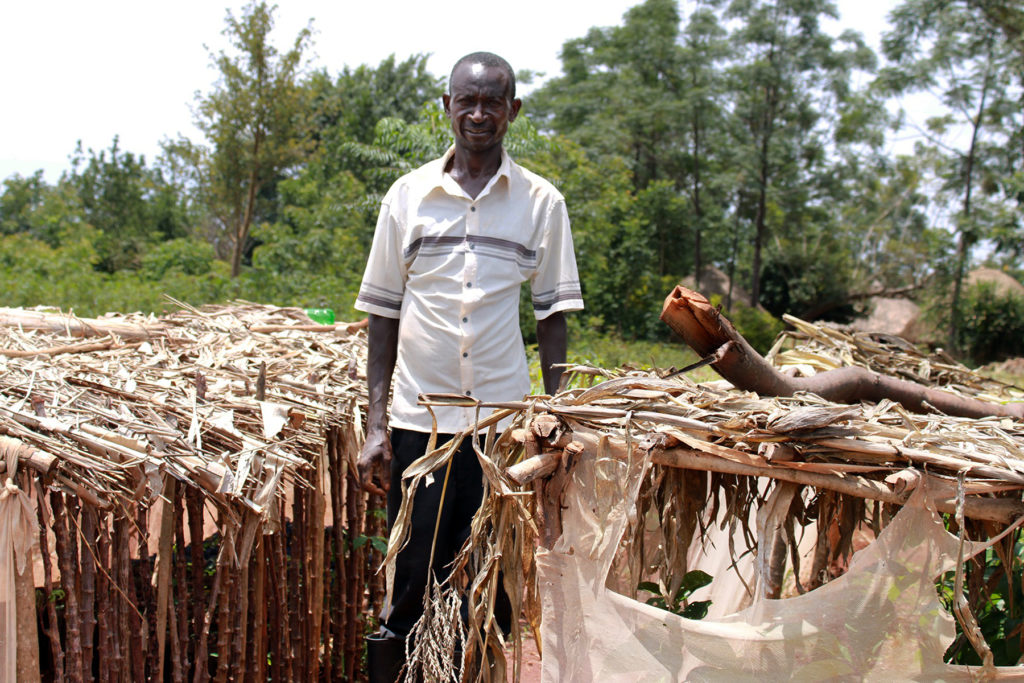 Ugandan farmer Gusino Hamphrecy standing next to plant nurseries he built himself