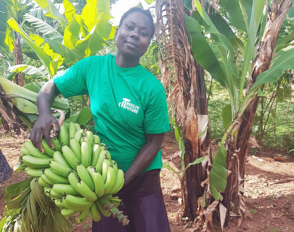 Kenyan farmer Theresa holding a bunch of bananas she grew