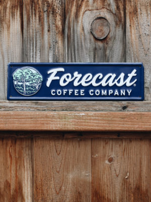 Navy blue tin tacker with Forecast logo sitting on a wooden fence